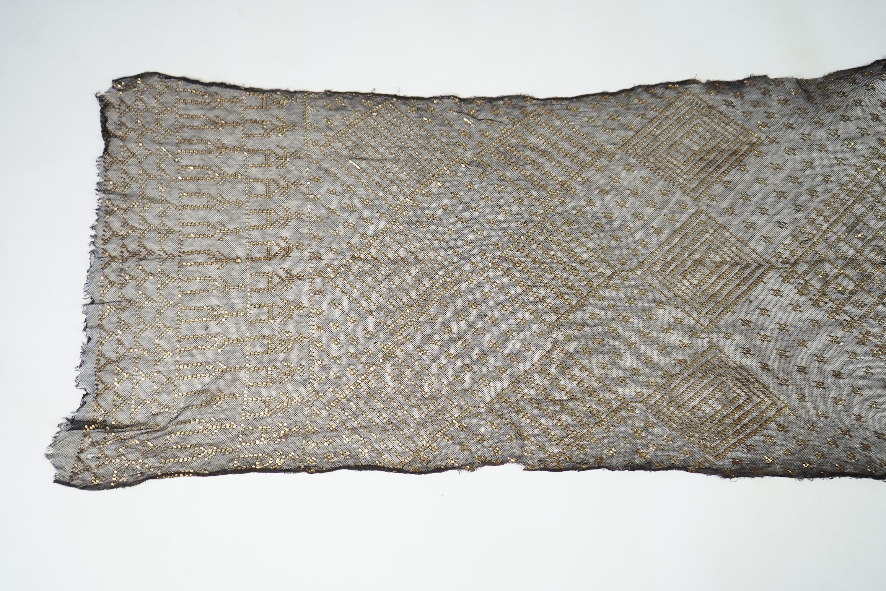 A 1930’s Egyptian decorative metal on black net evening stole. Approximately 218cm long. Condition - the rolled edges are frayed but the colour and design are intact.